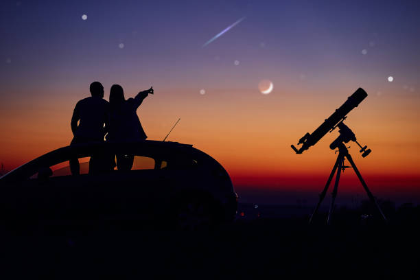 istock Couple stargazing together with a astronomical telescope. 1384162840