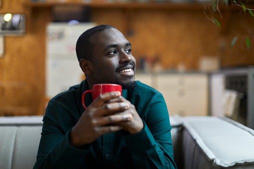 A smiling young man sits and holds a mug.