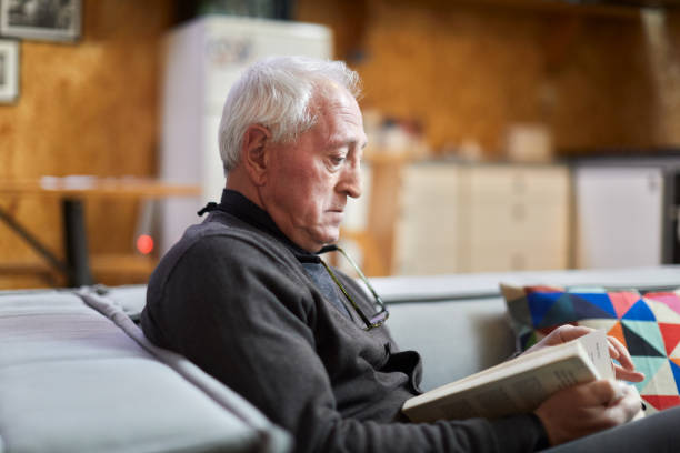 istock A retired man is reading a book at home. 1384176484