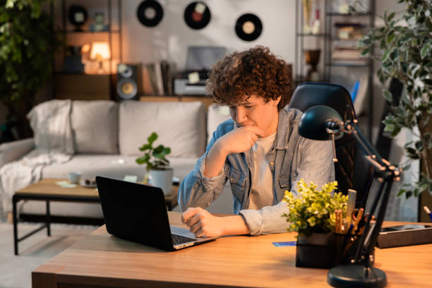 A man sits thoughtfully in front of a latop on a leather chair. He is having trouble logging into his internt account. He is thinking how to solve this problem