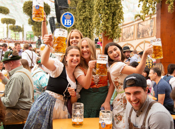 München, Deutschland - 21. September 2019: Oktoberfest in München, Deutschland. Eine Gruppe junger Leute in der Bierhalle feiert das Oktoberfest auf der Theresienwiese. Die Menschen sind in traditionelle Kleidung gekleidet und halten Bierglas in der Hand. Das Oktoberfest ist die größte Messe der Welt und findet jährlich in München statt.
