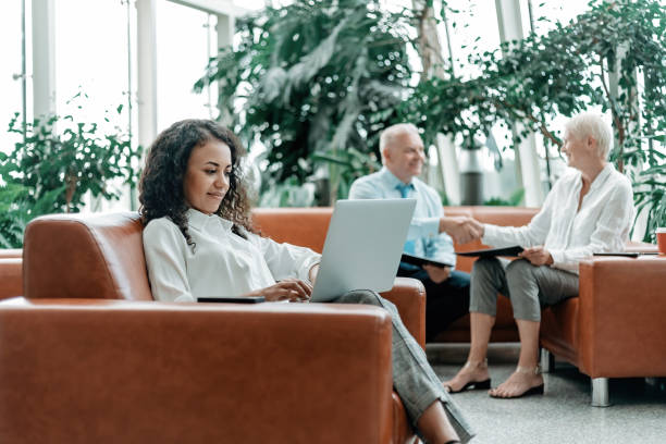 young businesswoman using a laptop while sitting in the lobby of a business center stock photo