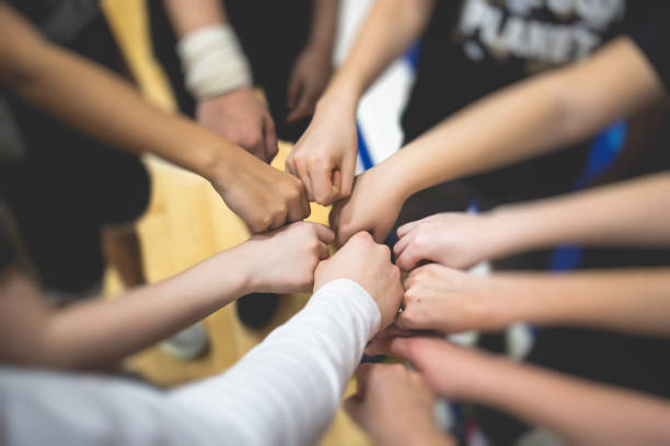 team of kids children basketball players stacking hands in the court, sports team together holding hands getting ready for the game, playing indoor basketball, team talk with coach, close up of hands - team sport imagens e fotografias de stock