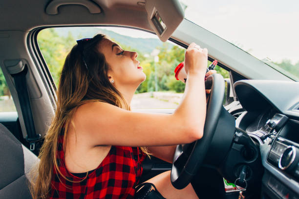 istock Cute Caucasian girl doing makeup while driving car on the road 1384209922