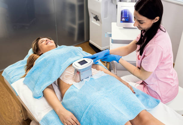 Beautician applying cryolipolysis treatment in beauty salon. stock photo