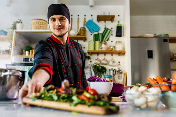 istock Cheerful young chef smiling at camera while serving you a steak salad 1384224300