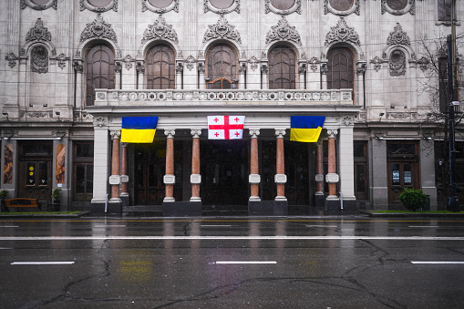 TBILISI, GEORGIA - MARCH 11, 2021. Ukrainian and Georgian flags are waving hang on houses, buildings, shop windows, apartment balcony in support of Ukraine