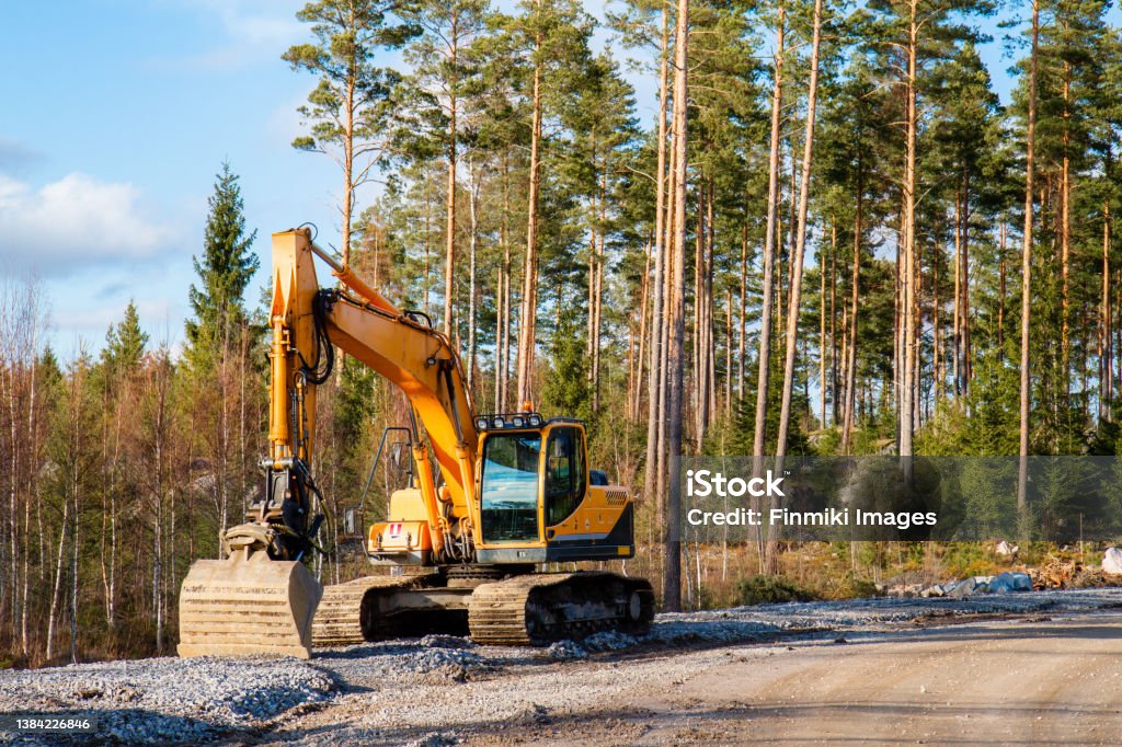 Yellow excavator Yellow excavator building a road deep in the forest. Rusko, Finland. Backhoe Stock Photo