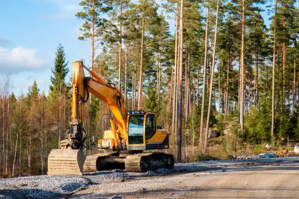 Yellow excavator building a road deep in the forest. Rusko, Finland.