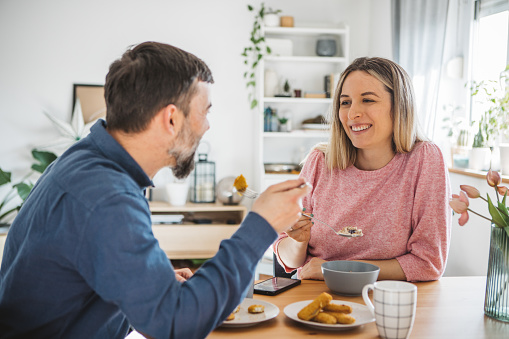 Young couple at home having breakfast. They are talking and smiling.