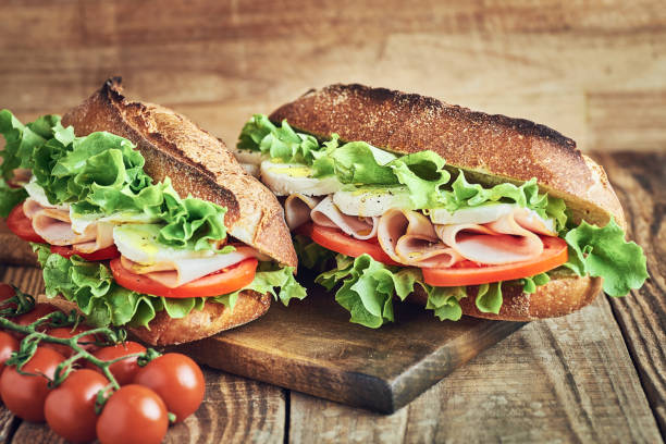 istock Two fresh sandwiches with ham on wooden table. 1384230947