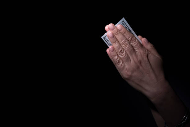 Hand holding tiny 20 dollar bills to represent loss of spending power on white background.\nThis is to represent shrinkflation, the fact that, to make more money, the manufacturers are reducing the package and keeping the same price of goods.\nThe consumers are then losing spending power.