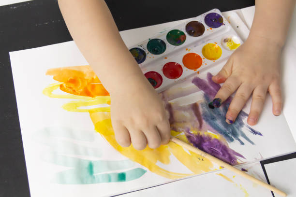 istock A little boy paints with watercolor paints on a table. 1384233001