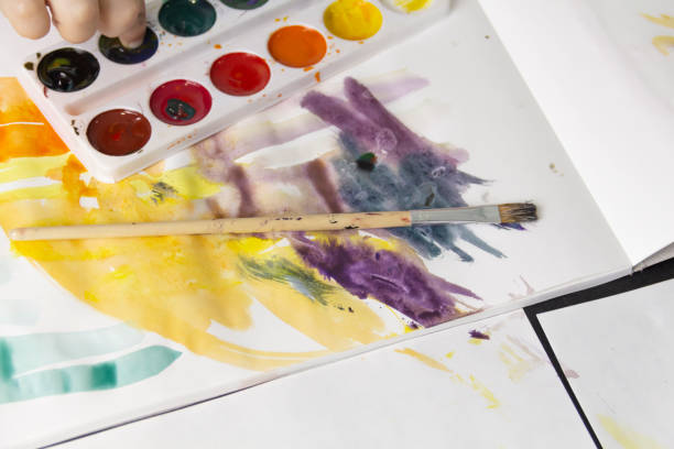 istock A little boy paints with watercolor paints on a table. 1384233017