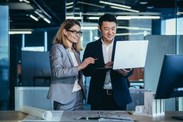 istock A team of multiracial business architects and designers discuss creating a project draft drawing by looking at laptop monitor screen a computer desk. Asian male and female developers together teamwork 1384233140