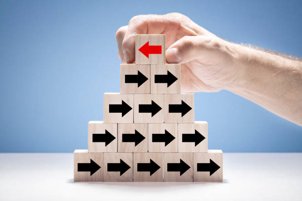 istock Individuality red arrow going different direction to black arrows on pyramid blocks 1384233247
