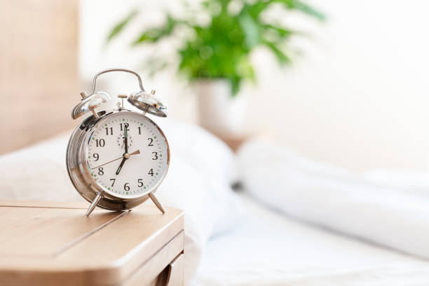 Alarm clock morning wake-up time on bedside table background Alarm clock morning wake-up time on bedside table by bed background early morning stock pictures, royalty-free photos & images