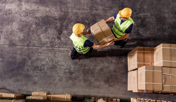 istock Above view of manual workers working with cardboard boxes in distribution warehouse. 1384235810