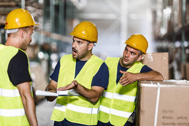 istock Frustrated manual workers arguing with their colleague in a warehouse. 1384237117