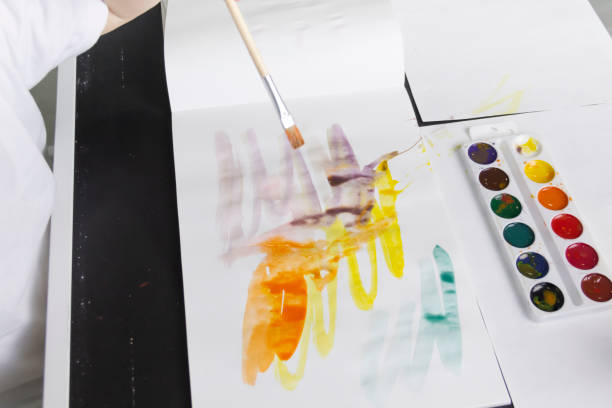 istock A little boy paints with watercolor paints on a table. 1384238318