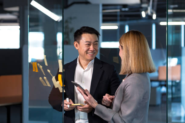 Team of business workers develop a business strategy, and develop a plan, an Asian man smiles at a female companion