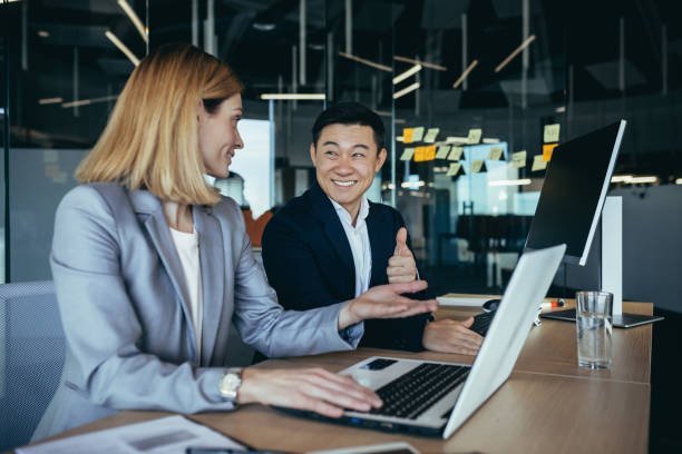 istock happy coworkers discuss project strategy by looking and pointing at laptop pc computer monitor screen. multiethnic business team in the office. confident mature asian man explaining young female 1384238758