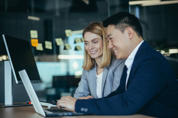 istock happy coworkers discuss project strategy by looking and pointing at laptop pc computer monitor screen. multiethnic business team in the office. confident mature asian man explaining young female 1384238766