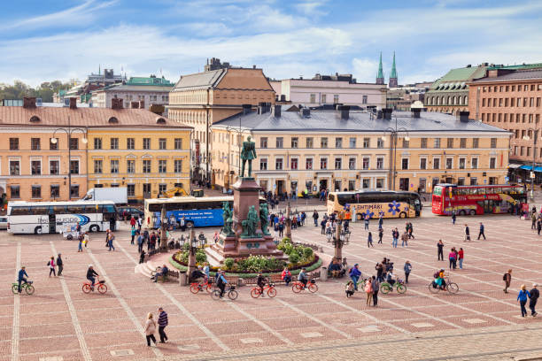 20 September 2018: Helsinki, Finland - Senate Square, with the statue of Alexander II, tour buses, and lots of tourists, including a cycle tour.