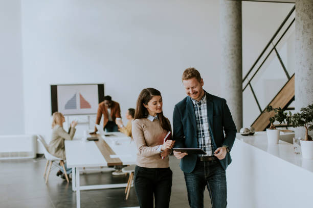 istock Young entrepreneur couple walking together and using digital tablet in the modern office 1384243942