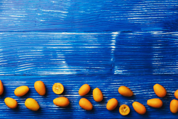 posa piatta azzurra con vista dall'alto su agrumi kumquat maturi freschi - citrus fruit frame portion isolated foto e immagini stock