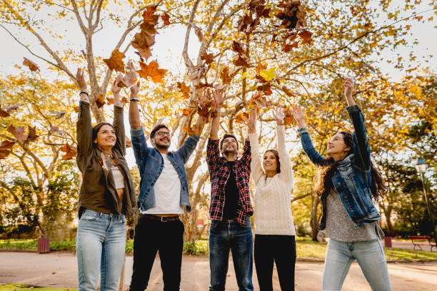 istock Friends having fun throwing leaves in the air 1384247746