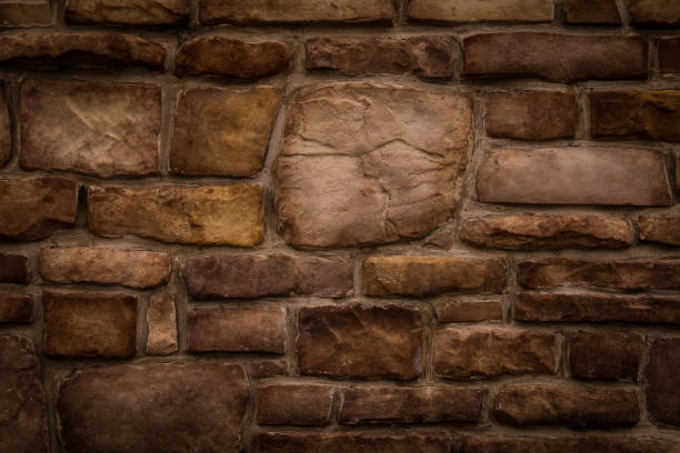 istock old odd shaped tan and brown thick cut stone block wall 1384248705