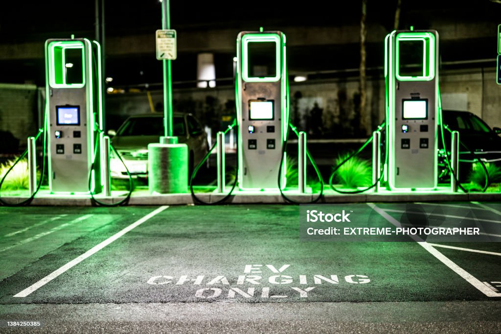 Electric car charging station Electric vehicle charging station seen during the night on a public parking with green lights. Electric Vehicle Charging Station Stock Photo