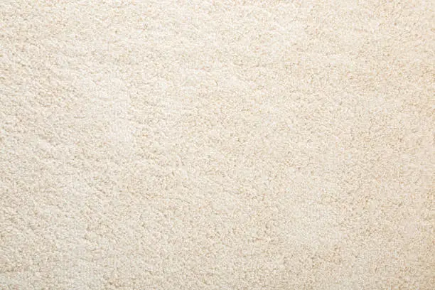 Photo of Beige new fluffy home carpet background. Closeup. Empty place for text. Top down view.