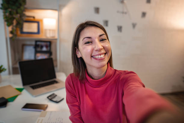 istock Beautiful smiling brunette taking a selfie while working from home 1384251725