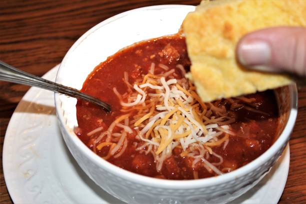 Engaging Food Art Photographs for Media Projects and Restaurant Menu Use - Hot Chili and Corn Bread - Daily Special on Our Menu for Today - Best Bowl of Chili in Towne - Serving of Soup - Close Up Personal Perspective of Chili Bowl with Wonderful Corn Bread - Eating Lunch - Eating At The Diner - Bowl of Chili - Homemade Chili topped with Shredded Cheese - Family Favorite Meal - Comfort Foods in America - Fantastic Food Background Art - Lunch Served by My Waitress fotografía libre de derechos - los mejores fondos de comida para sitio web, menú, blogs de comida o marketing - delicioso chile y pan de maíz caliente para el almuerzo - fotos de sopa y pan - comer chile picante en un frío día de invierno - mi pan de