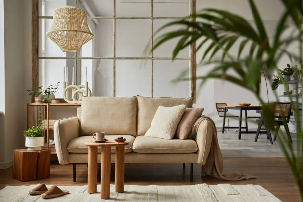 istock Elegant living room interior design with beige modern sofa, coffee table and creative accessories. Template. Copy space. Dining room in the background. 1384257705