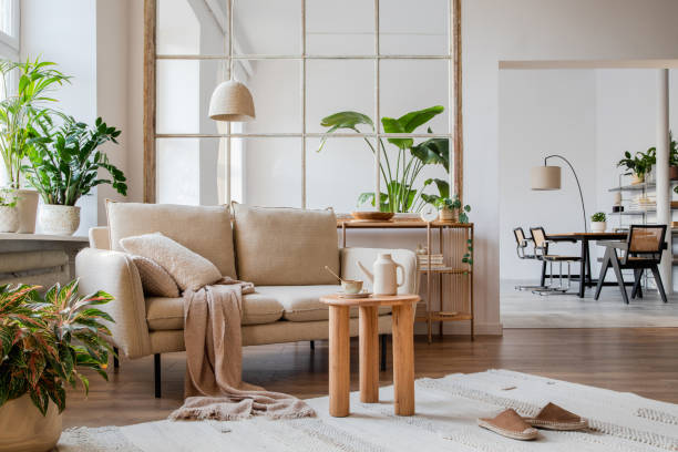 istock Elegant living room interior design with beige modern sofa, side table and creative accessories. Template. Copy space. Dining room in the background. 1384258097