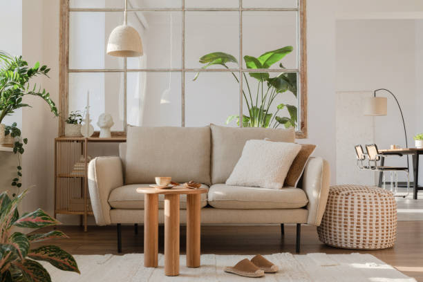 istock Elegant living room interior design with beige modern sofa, side table and creative accessories. Template. Copy space. Dining room in the background. 1384258160