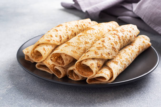 istock Thin pancakes rolled into a roll on a plate. The concept of a delicious breakfast or Maslenitsa. concrete background. 1384260496