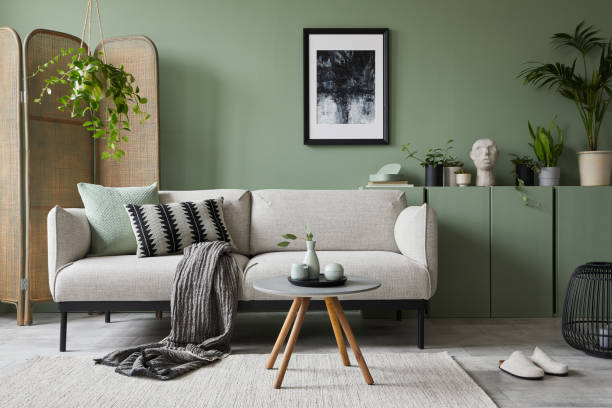 istock Elegant living room interior design with mockup poster frame, modern grey sofa, wooden commode, folding screen, plants and stylish accessories. Eucalyptus wall. Template. Copy space. 1384260519