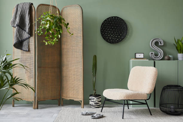 istock Creative living room interior composition with frotte armchair, folding screen, wooden commode and modern home accessories. Sage green wall. Template. Copy space. Real photo. 1384260587