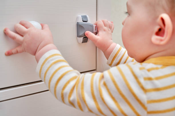 опасность для малыша ущипнуть рукой дверцу шкафа или комод. защита детей от домашней мебели, безопасность детей - child proof стоковые фото и изображения