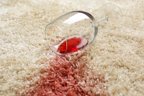 istock Overturned glass and spilled red wine on soft carpet, closeup 1384262030