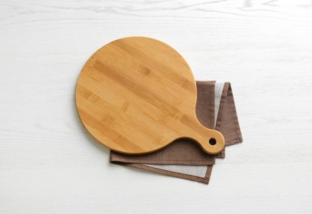 istock Empty wooden board and napkin on white table, top view 1384262350