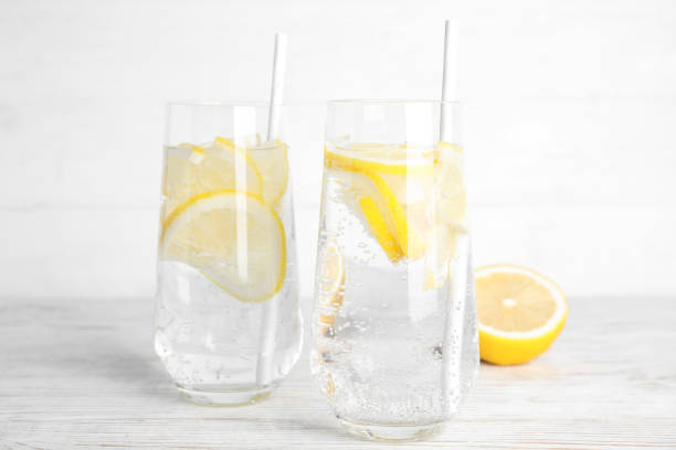 istock Soda water with lemon slices and fresh fruit on white wooden table 1384263168