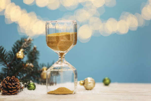 istock Hourglass, fir tree twigs and decor on white table against blurred lights, space for text. Christmas countdown 1384269266