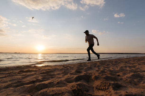 istock young athletic man running along a sandy beach 1384269663