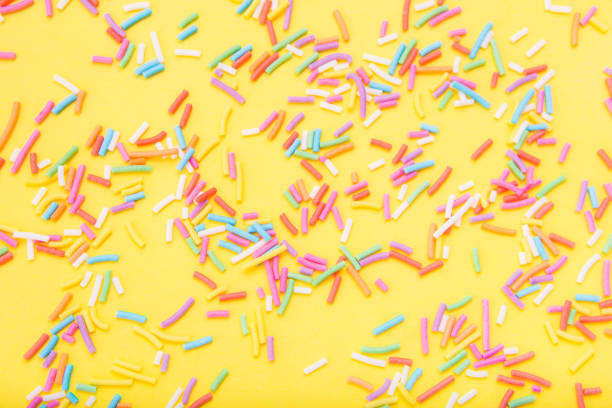 istock Colorful festive sugar sprinkles  on yellow background. 1384271426