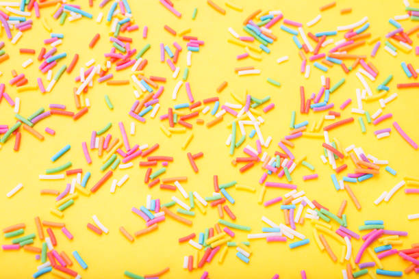 istock Colorful festive sugar sprinkles  on yellow background. 1384271428